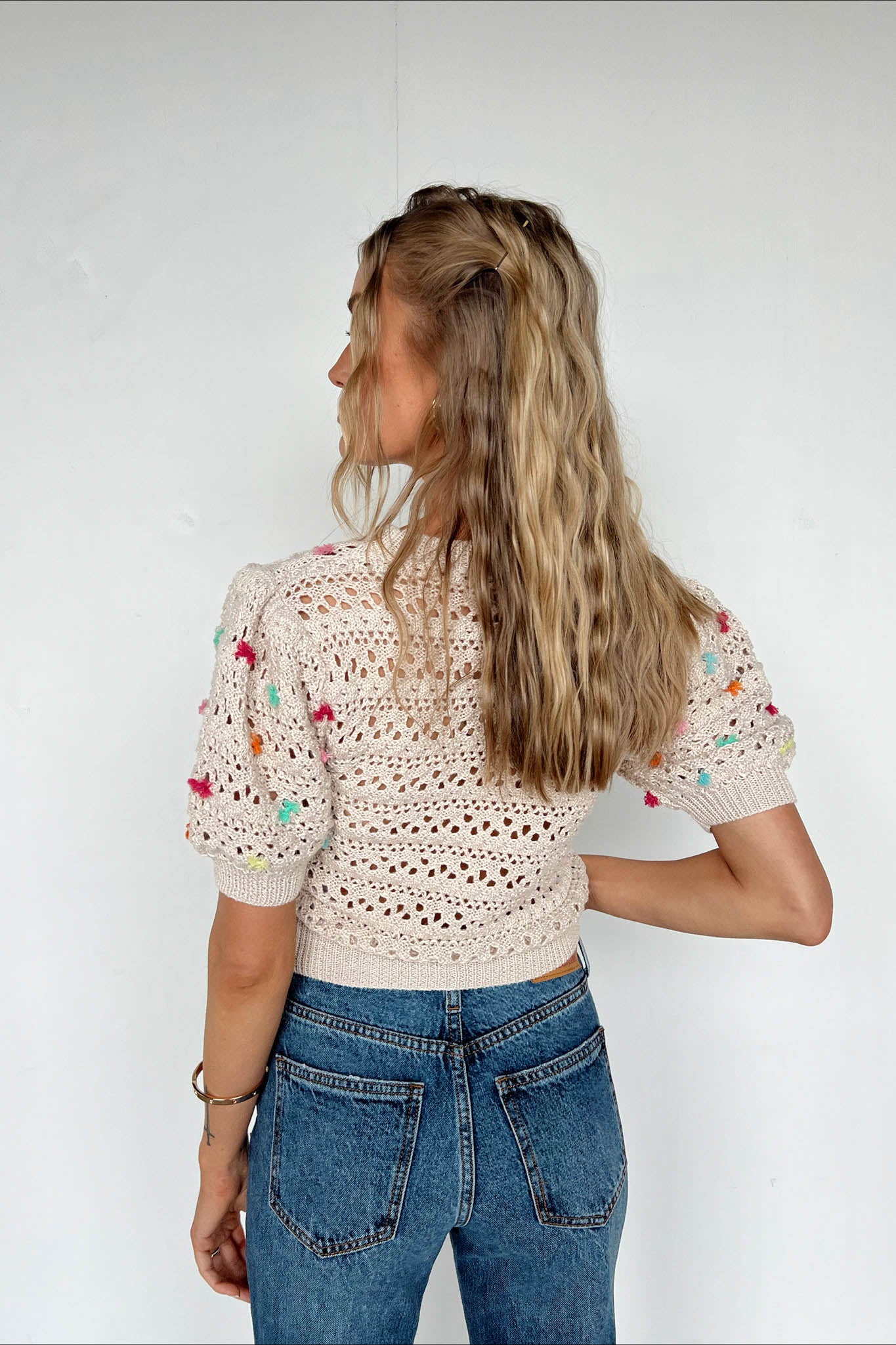 beige yarn top with colorful pom poms